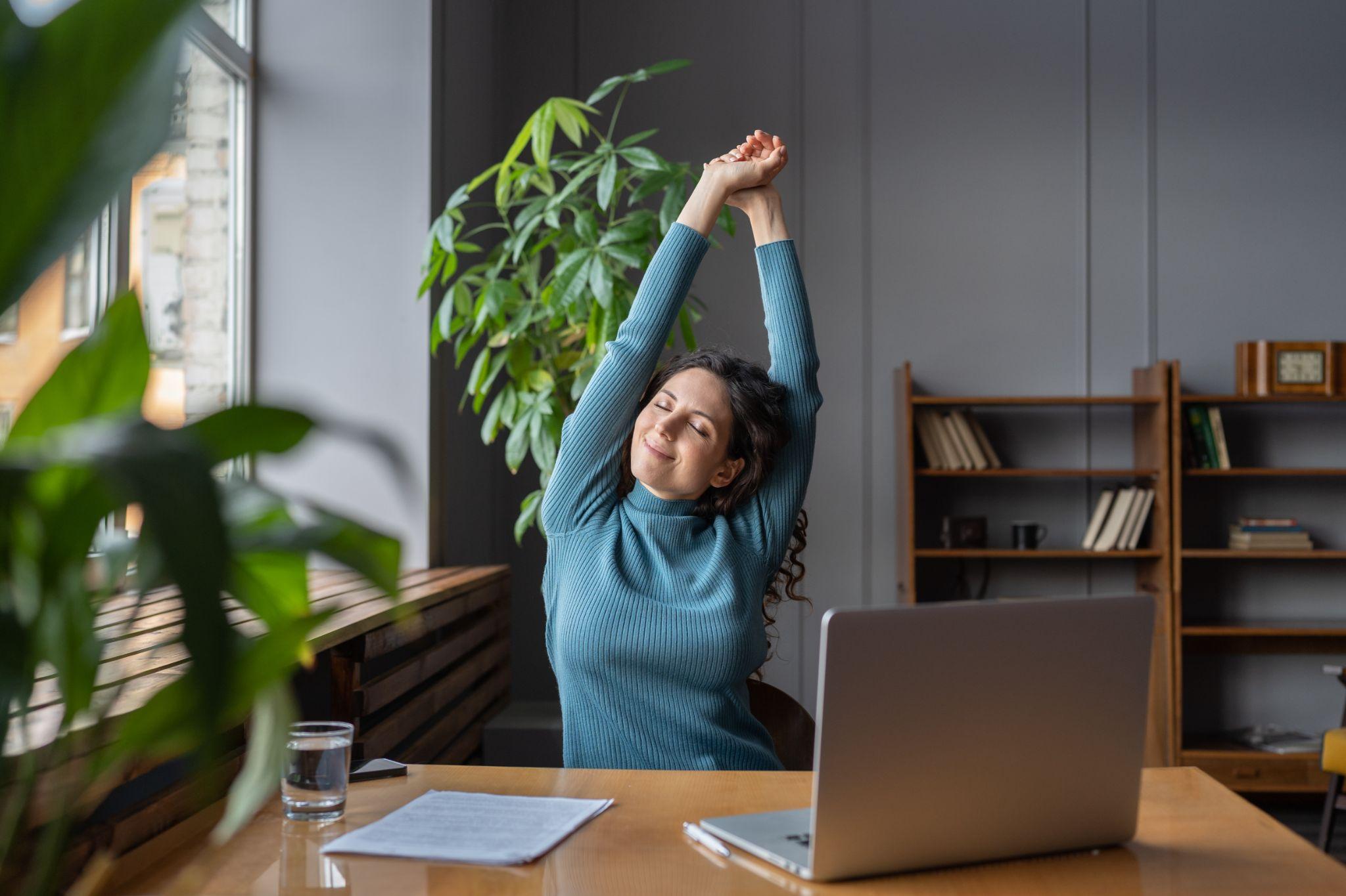 Businesswoman warming up body and muscles at workplace.