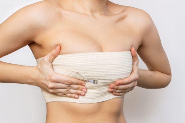 young woman wrapped in elastic bandage after breast augmentation