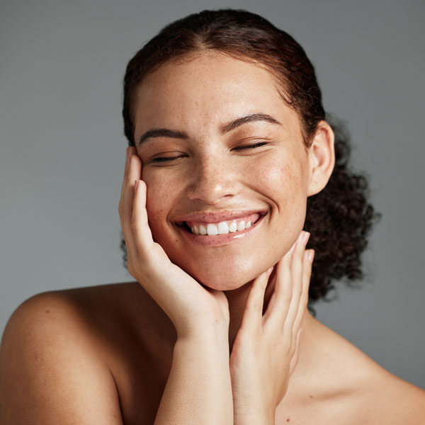 happy young woman smiling and holding face with eyes closed